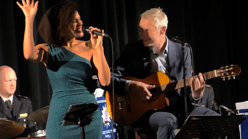 Sängerin Caroline Mhlanga im grünen Kleid performat mit Musiker Pit Grün daneben auf einem Hocker mit Gitarre in den Händen.